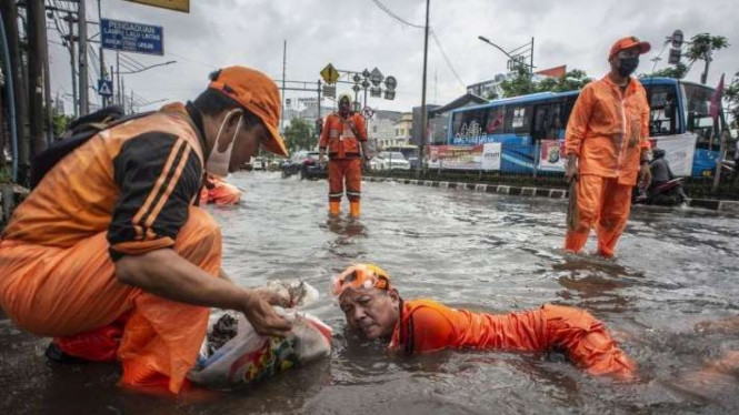 Petugas PPSU membersihkan sampah yang menyumbat saluran air. (Foto ilustrasi).